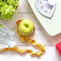 Green apple and Weight scale,measure tap with fresh vegetable, clean water and sport equipment for women diet slimming.  Diet and Healthy Concept